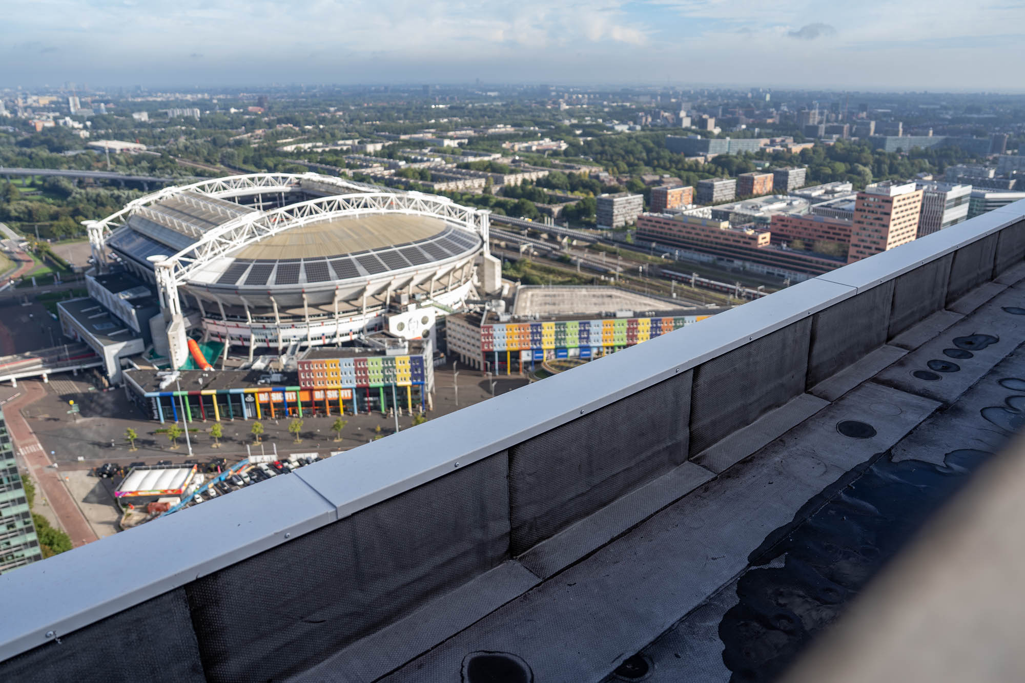 Dakrand met metalen afdekking op de Dreeftoren, met uitzicht op de Johan Cruijff ArenA en Amsterdam-Zuidoost.